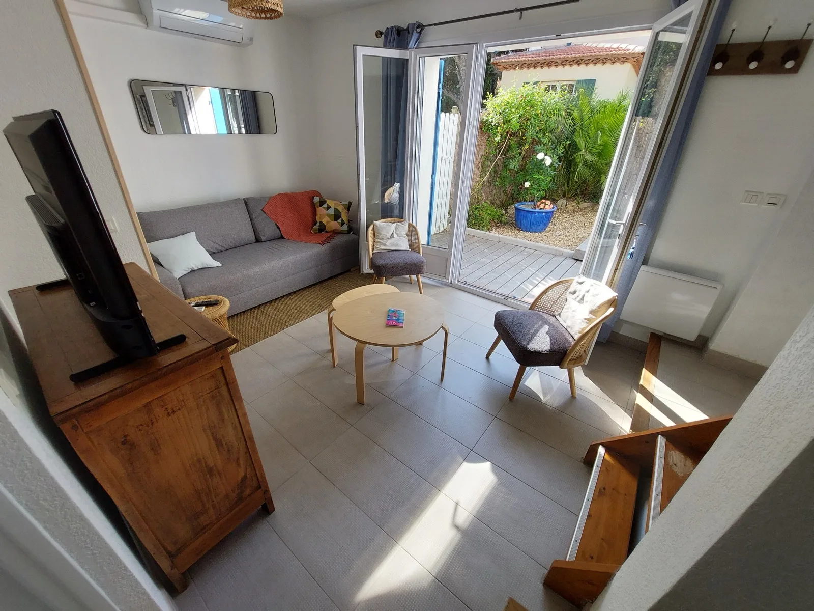 Wohnzimmer mit Öffnung zum Garten, Sofa, Sessel und Fernseher